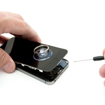 A pair of hands repairing a broken and damaged mobile phone or cell phone screen on white background