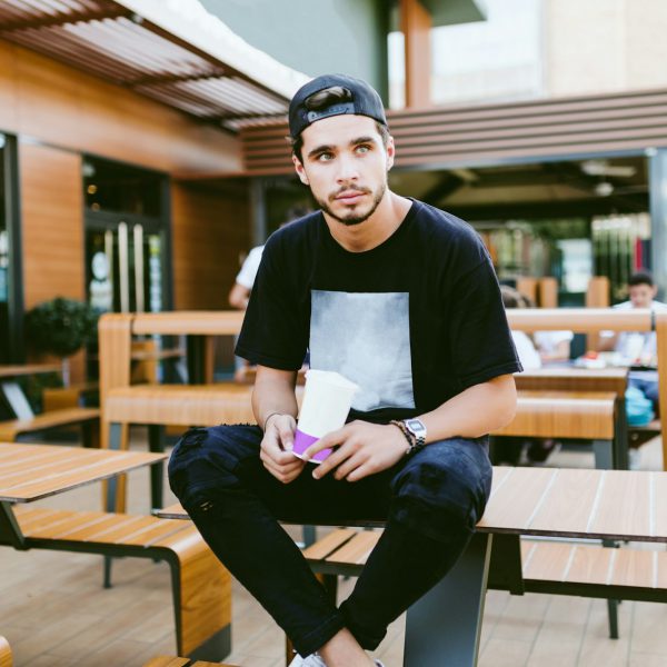 Handsome young man drinking refreshment at outdoor bar.